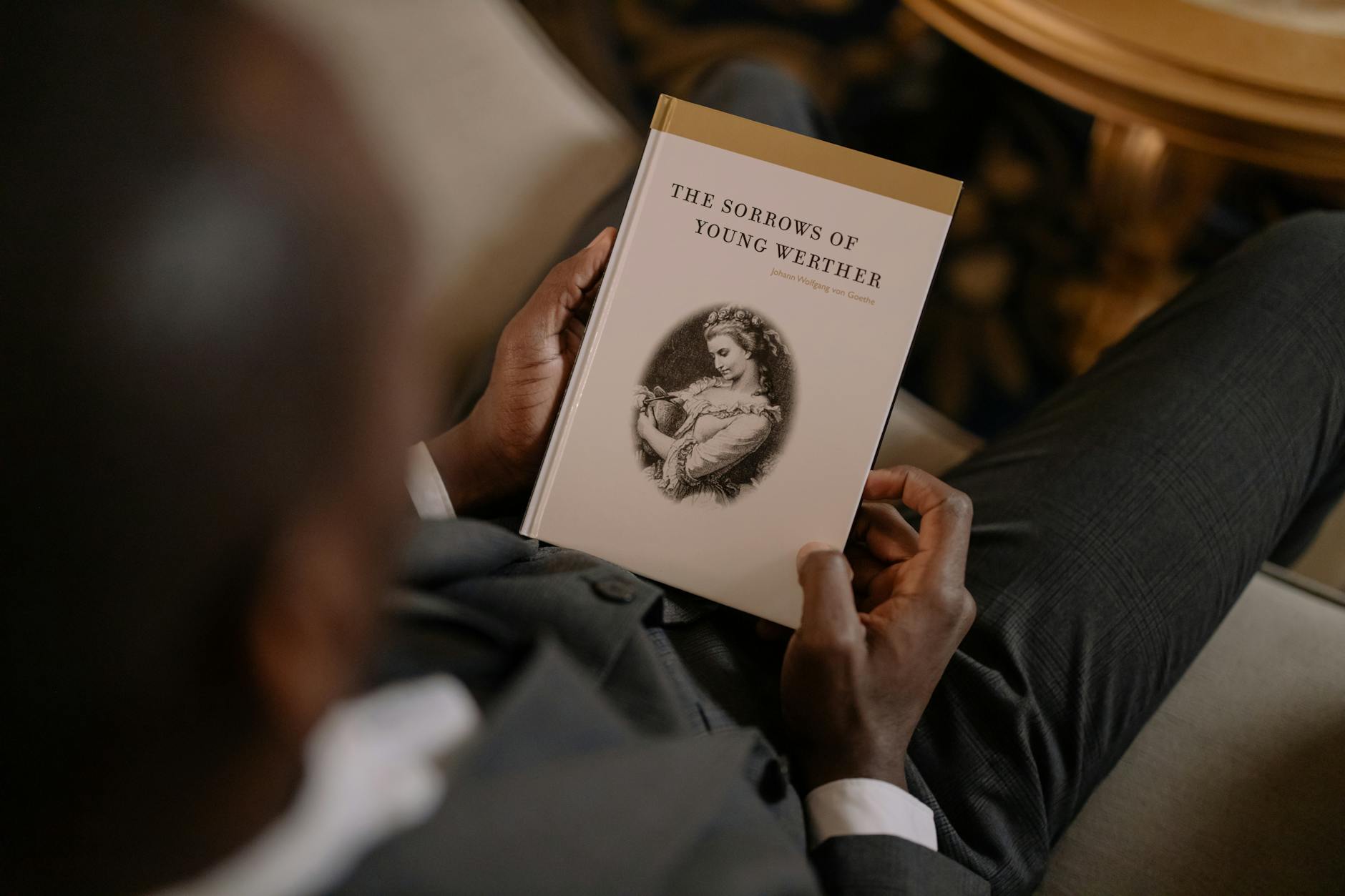 Elegancko ubrany mężczyzna czyta Cierpienia młodego Wertera w salonie