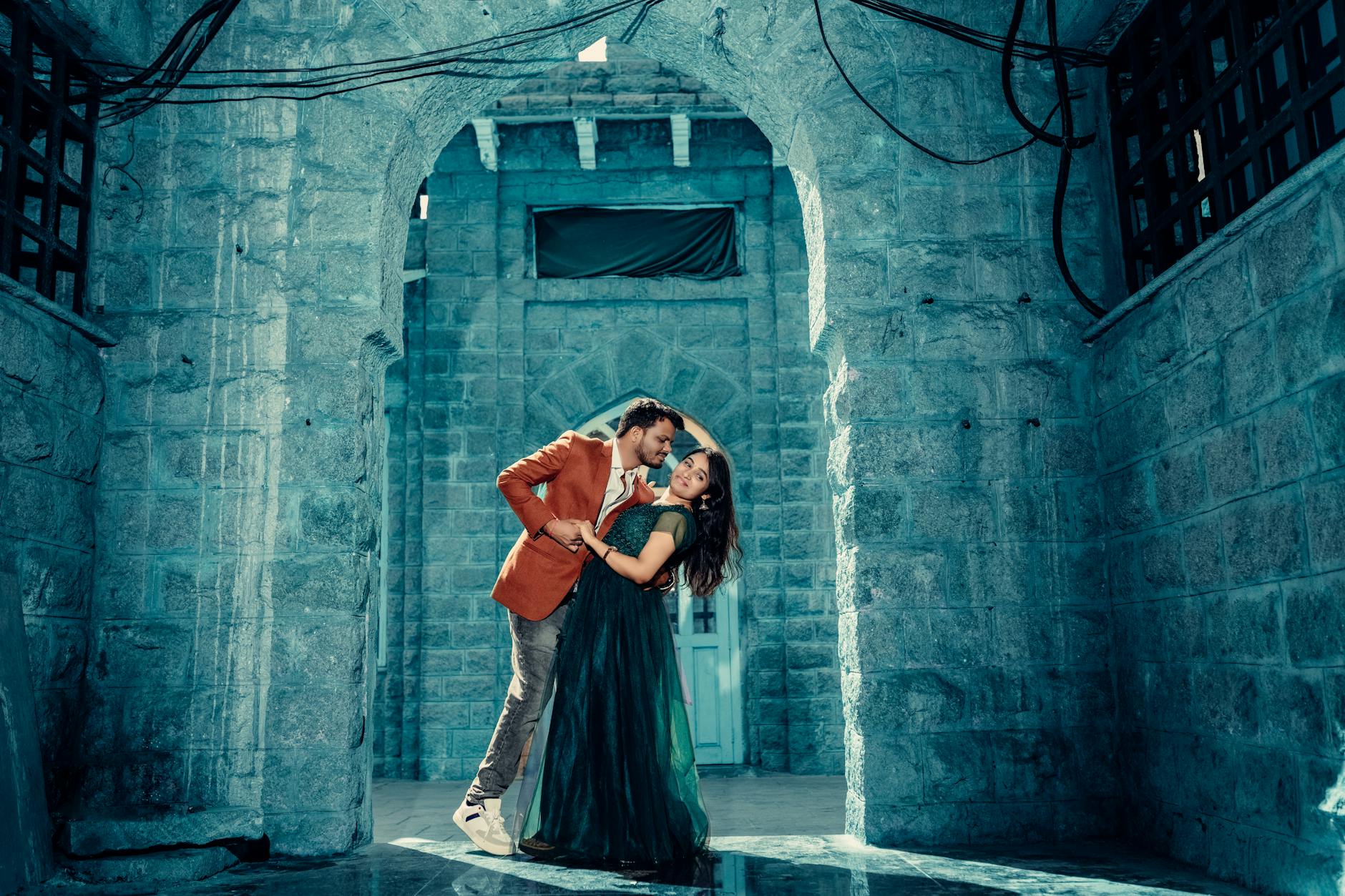 Elegancka para pozuje w kamiennym korytarzu romantycznego zamku