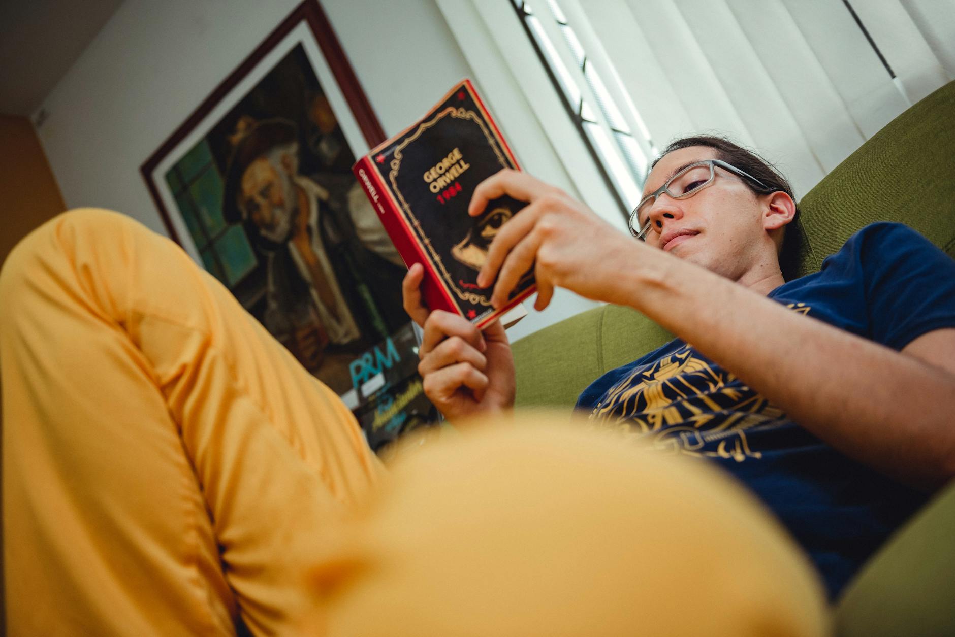 Mężczyzna w okularach czyta powieść w zaciszu domowym