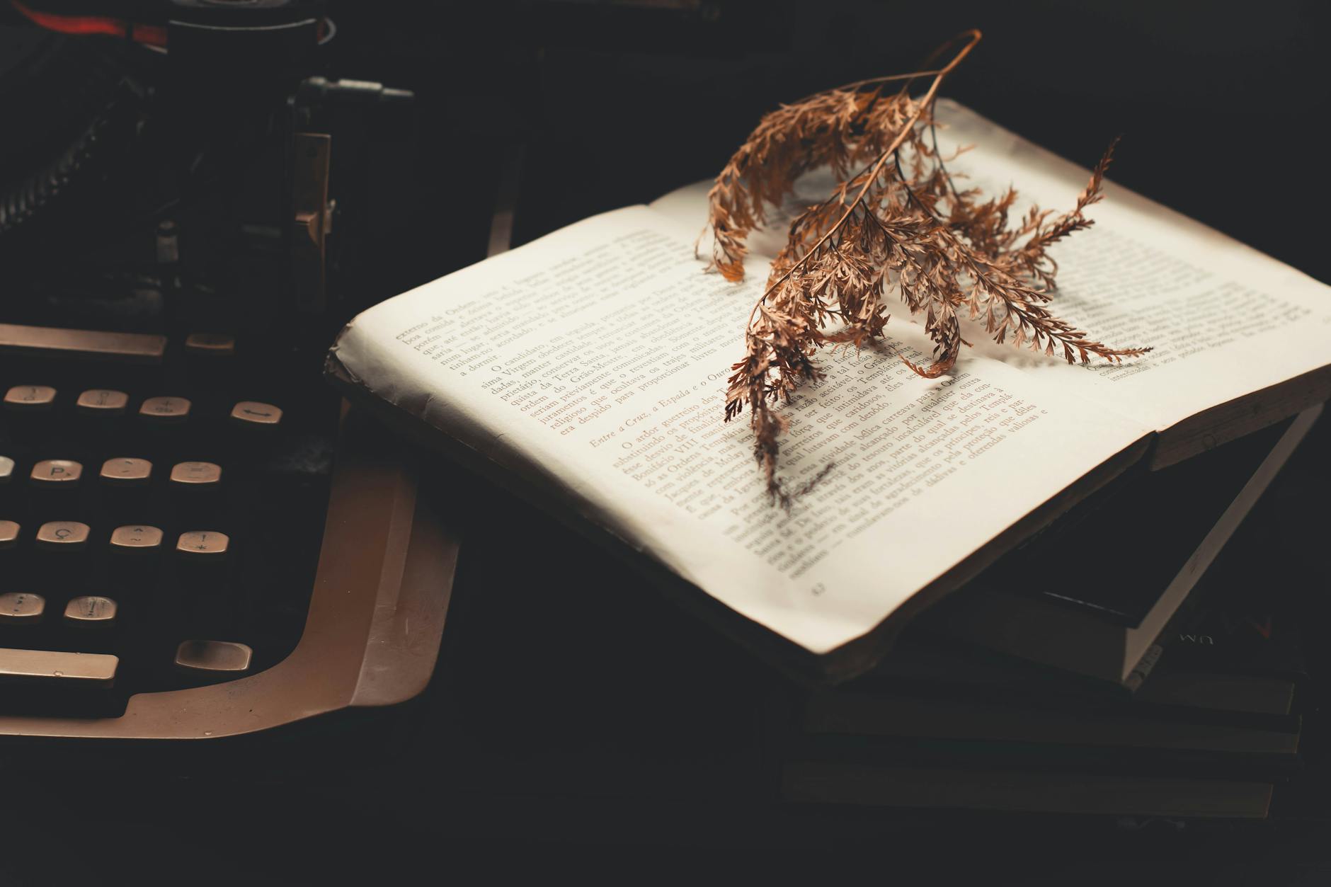 Otwarta książka i zasuszone liście na starej maszynie do pisania