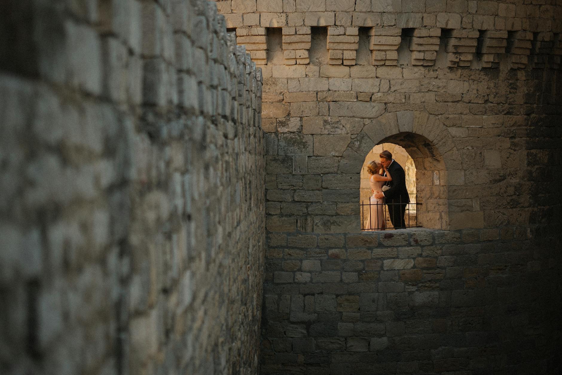 Para nowożeńców całuje się w kamiennym oknie starego zamku