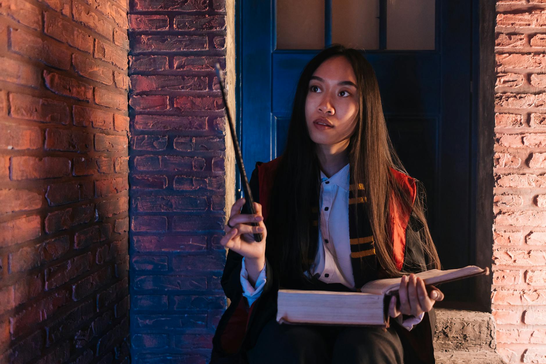 Azjatka w stroju czarodziejki z księgą i różdżką w magicznym wnętrzu