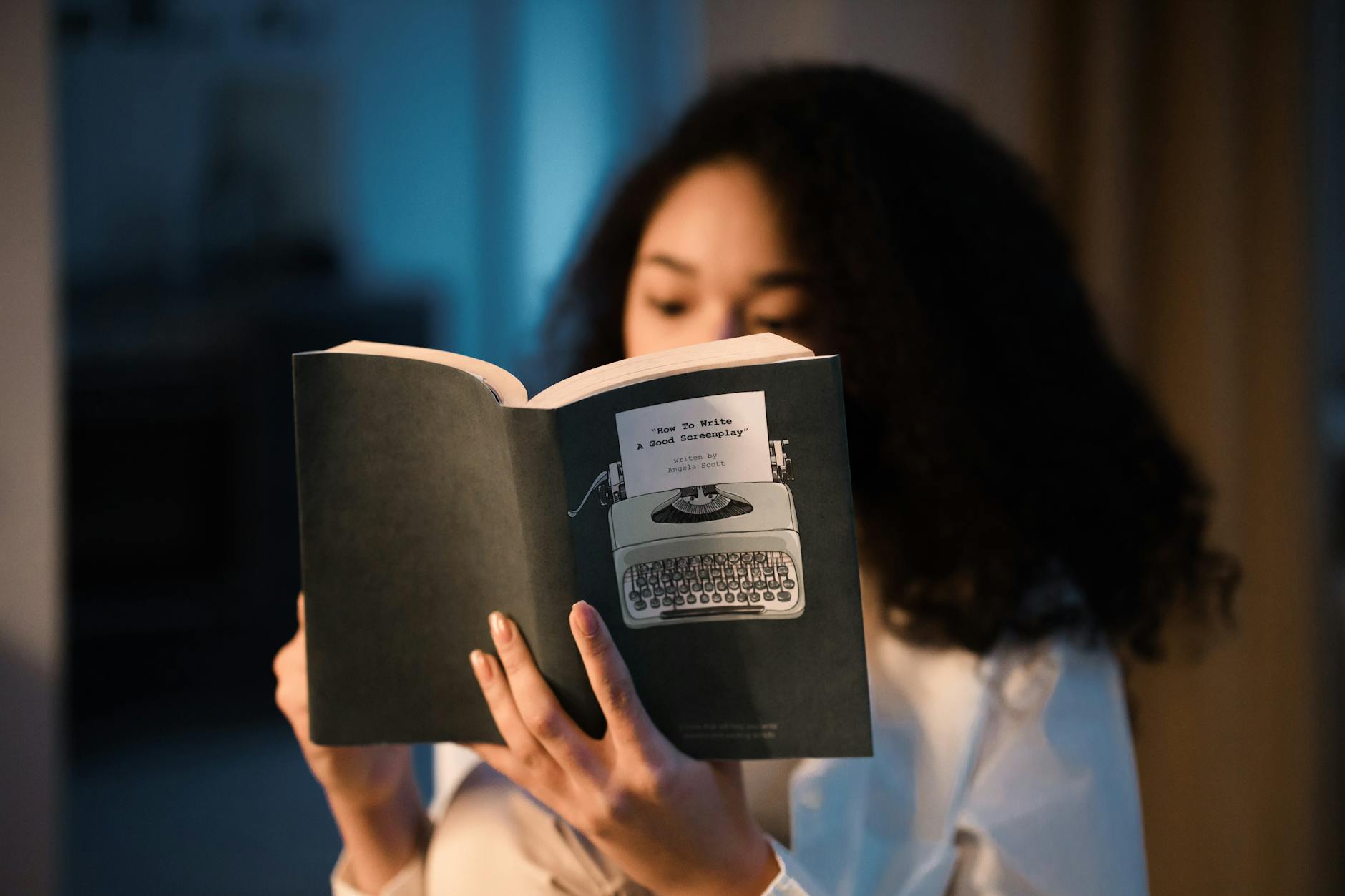 Kobieta o kręconych włosach czyta książkę kryminalną w domu