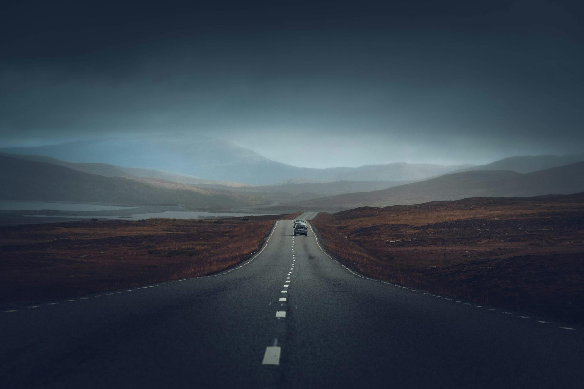 Prosta szosa prowadząca przez górski krajobraz o zachodzie słońca