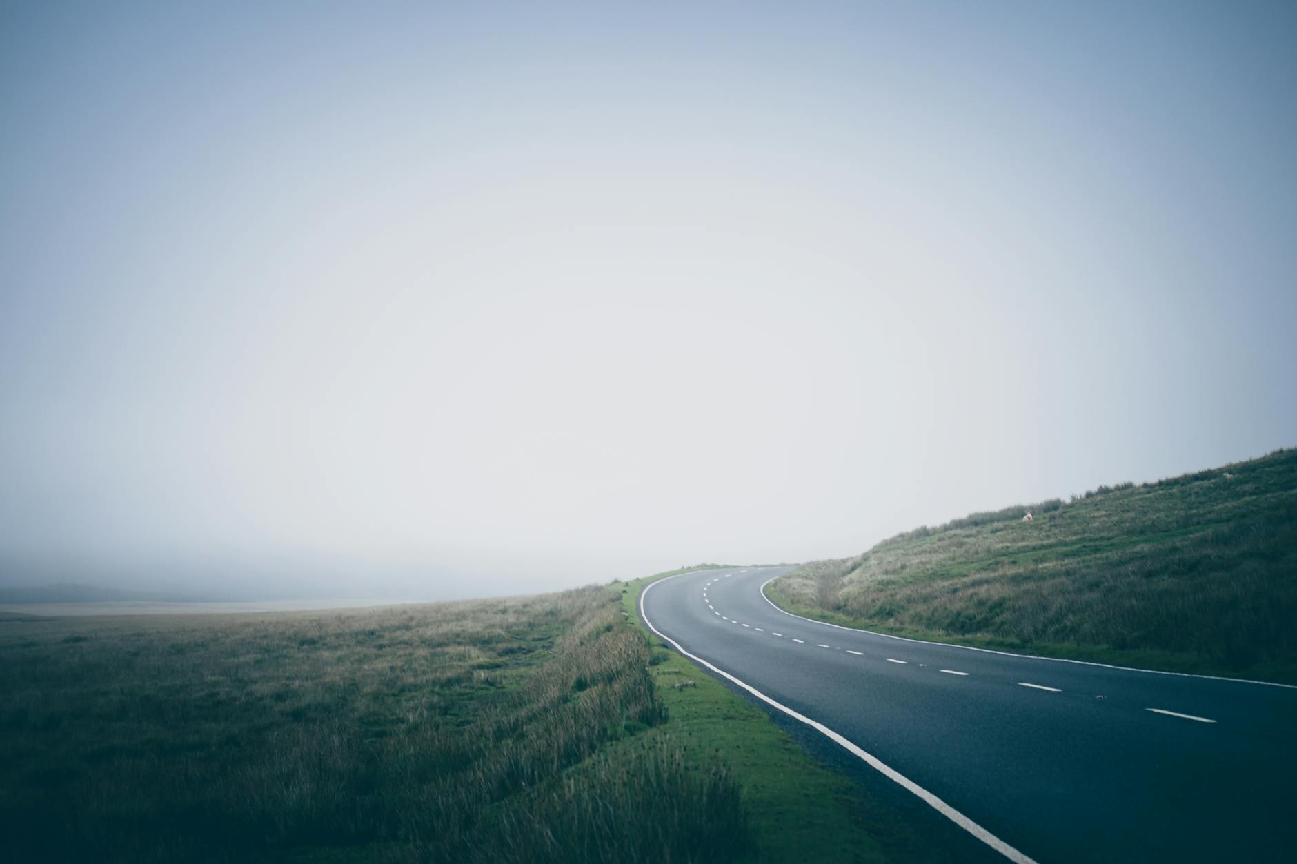Pusta, kręta droga we mgle na spokojnej, wiejskiej przestrzeni