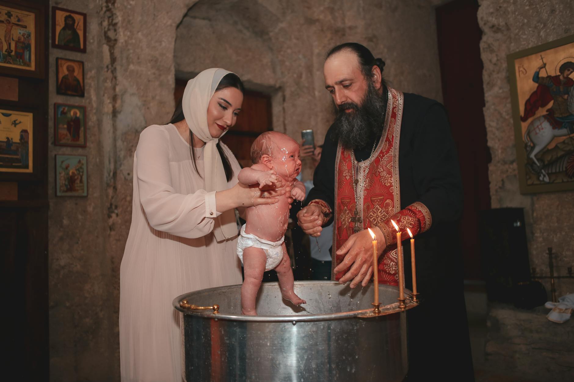 Rodzice i kapłan podczas chrztu dziecka w cerkwi