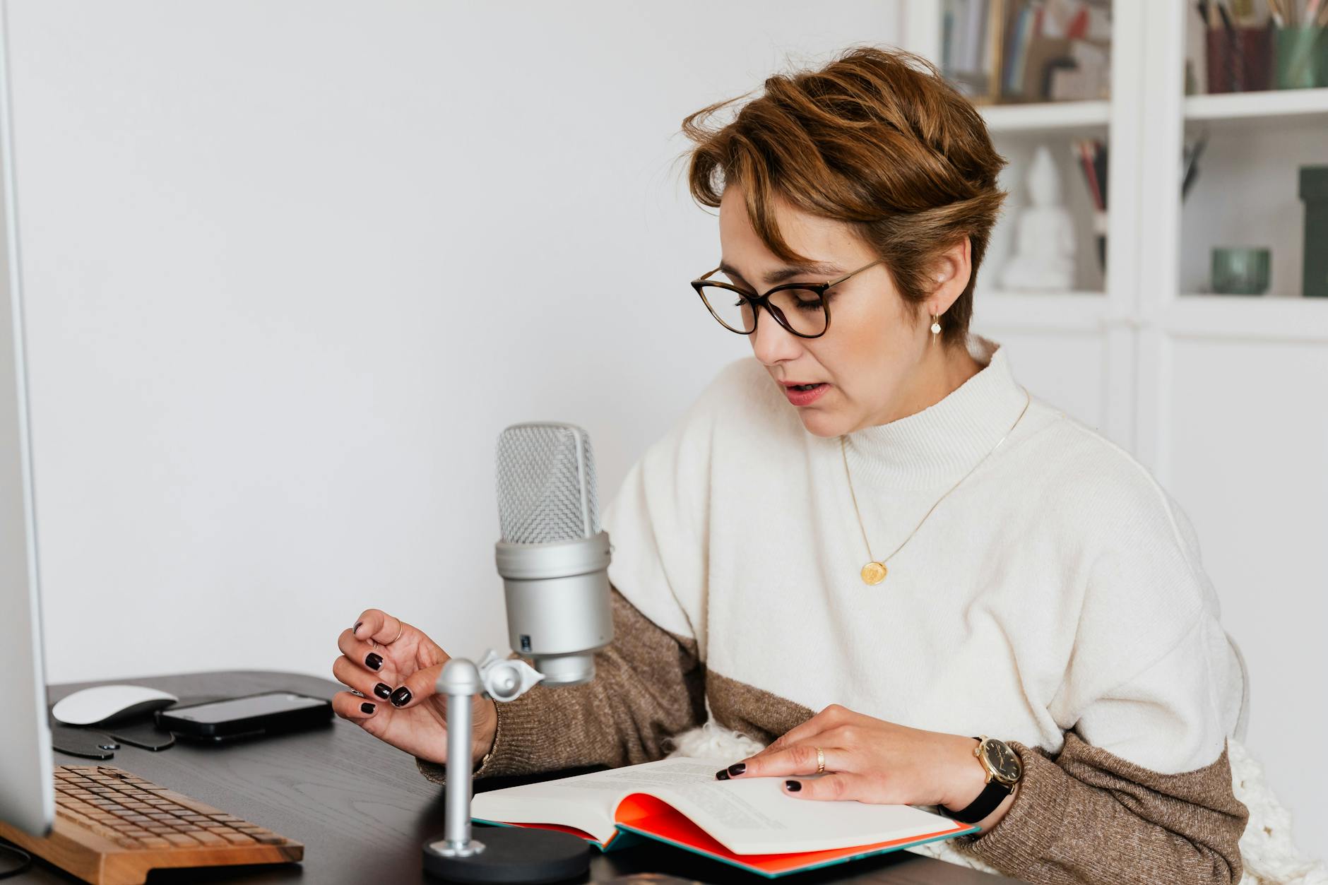 Lektorka w okularach nagrywa audiobook przy biurku w domowym gabinecie