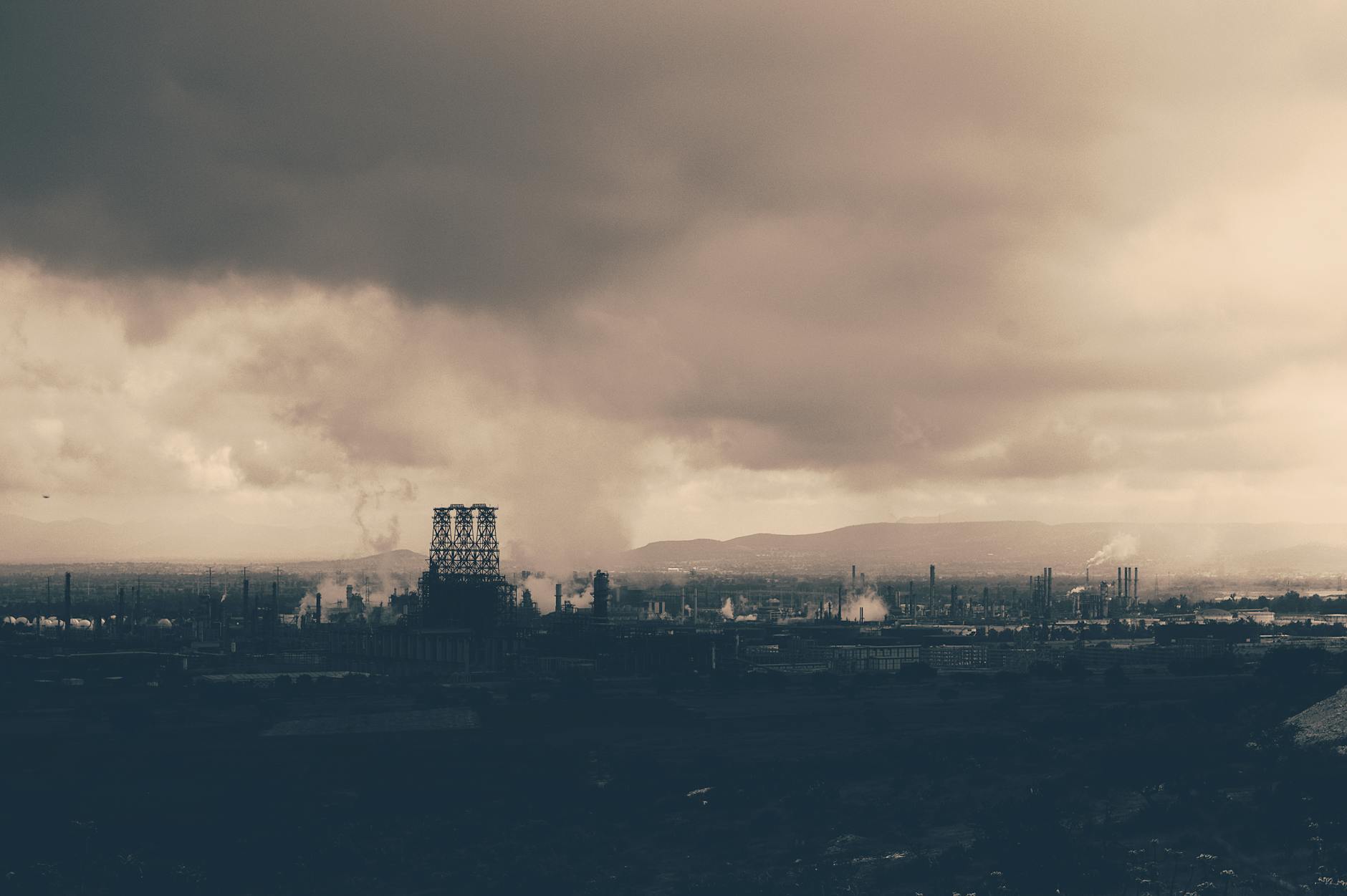 Monochromatyczny krajobraz z fabryką dymiącą na zanieczyszczone niebo