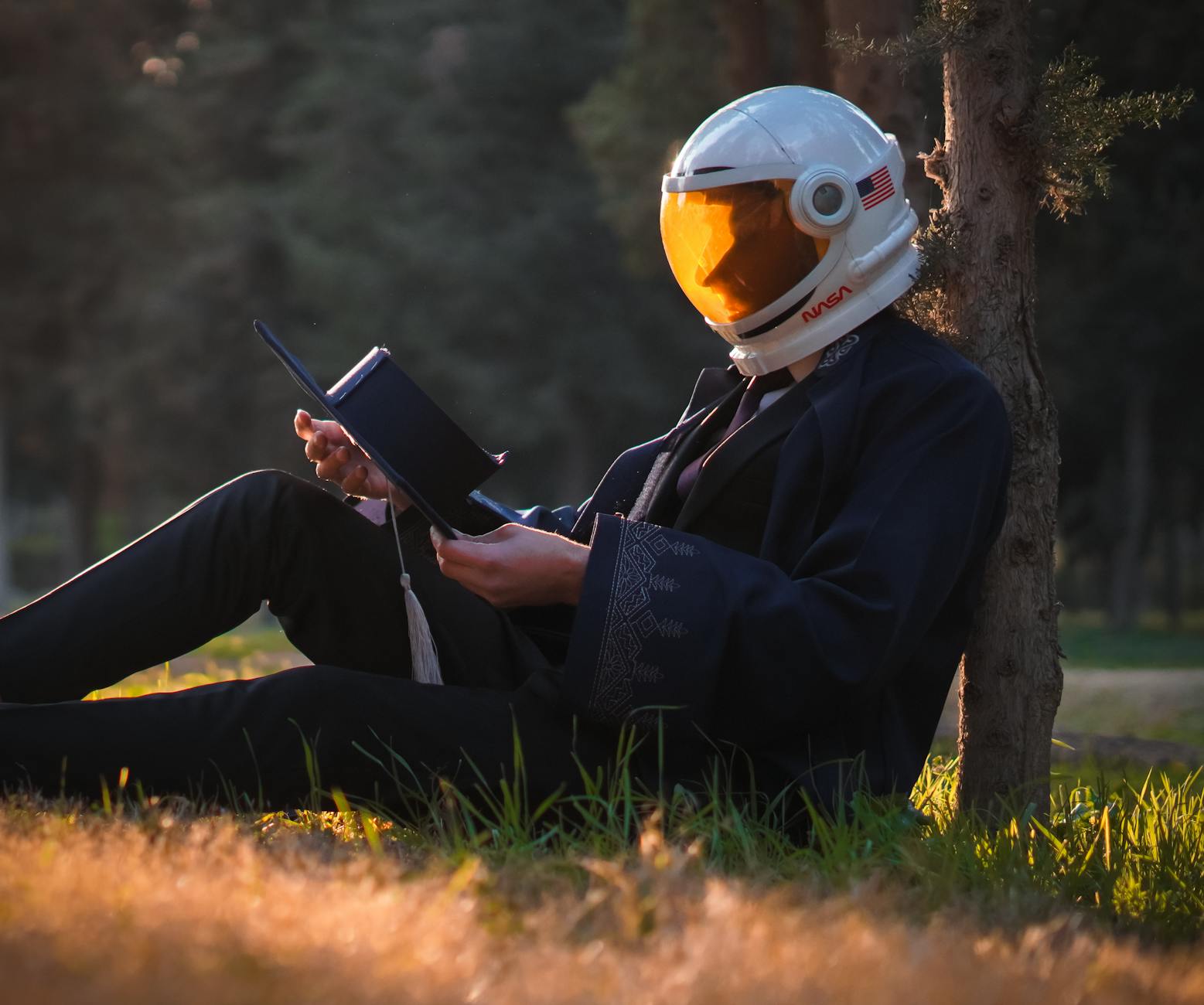 Recenzja: Kwiaty dla Algernona – jak ta historia zmienia czytelnika? Osoba w hełmie astronauty czyta książkę na łonie natury