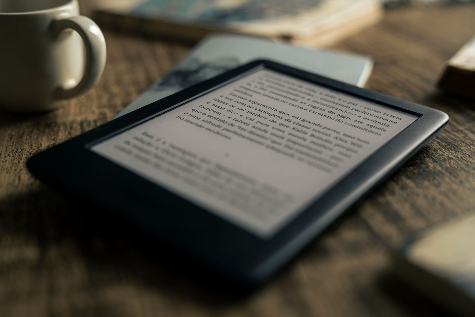 Tablet z otwartym ebookiem na drewnianym stole obok filiżanki kawy